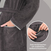 Detailansicht von Tasche am Bademantel mit Hand die Schlüssel zeigt