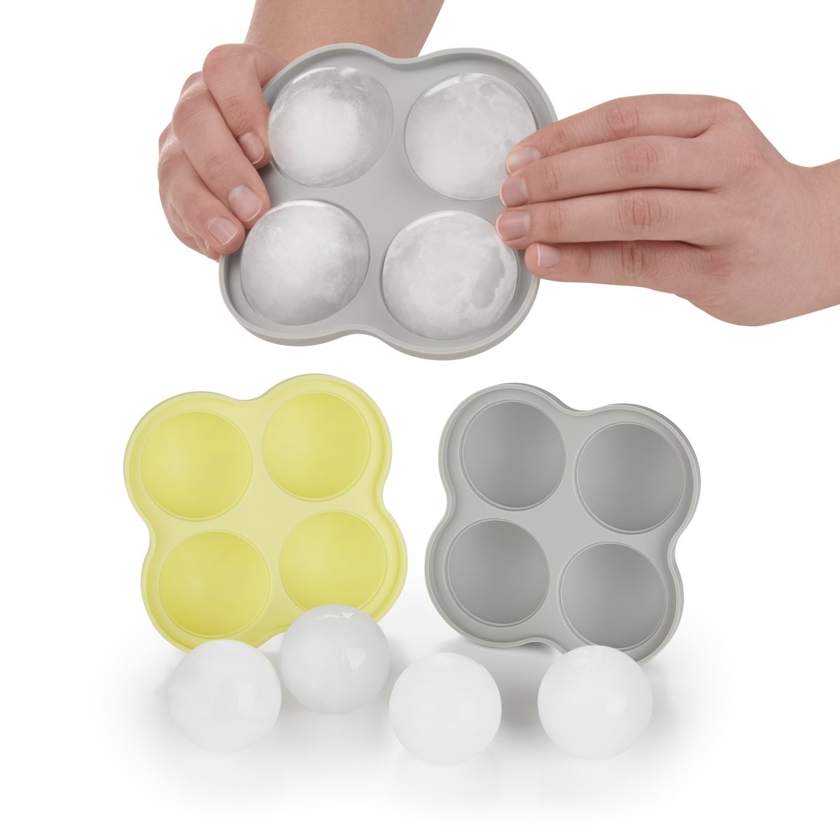 Hände entfernen Eiskugeln aus einer grauen Form.