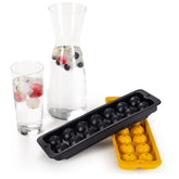 Schwarze und gelbe Eiswürfelformen neben Glaskaraffe mit Eiskugeln.