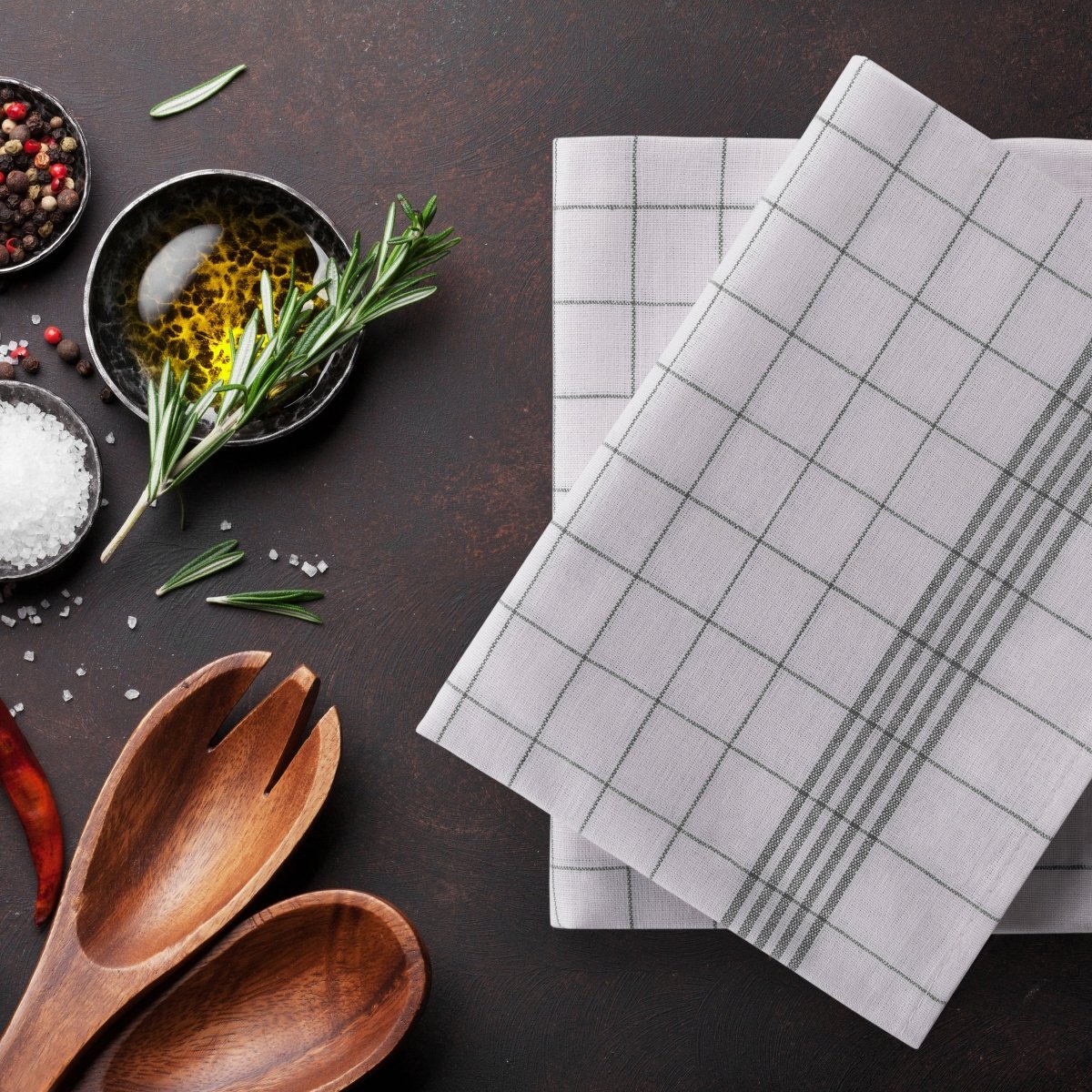 Geschirrtücher liegen auf einer Arbeitsfläche mit Kochzutaten.