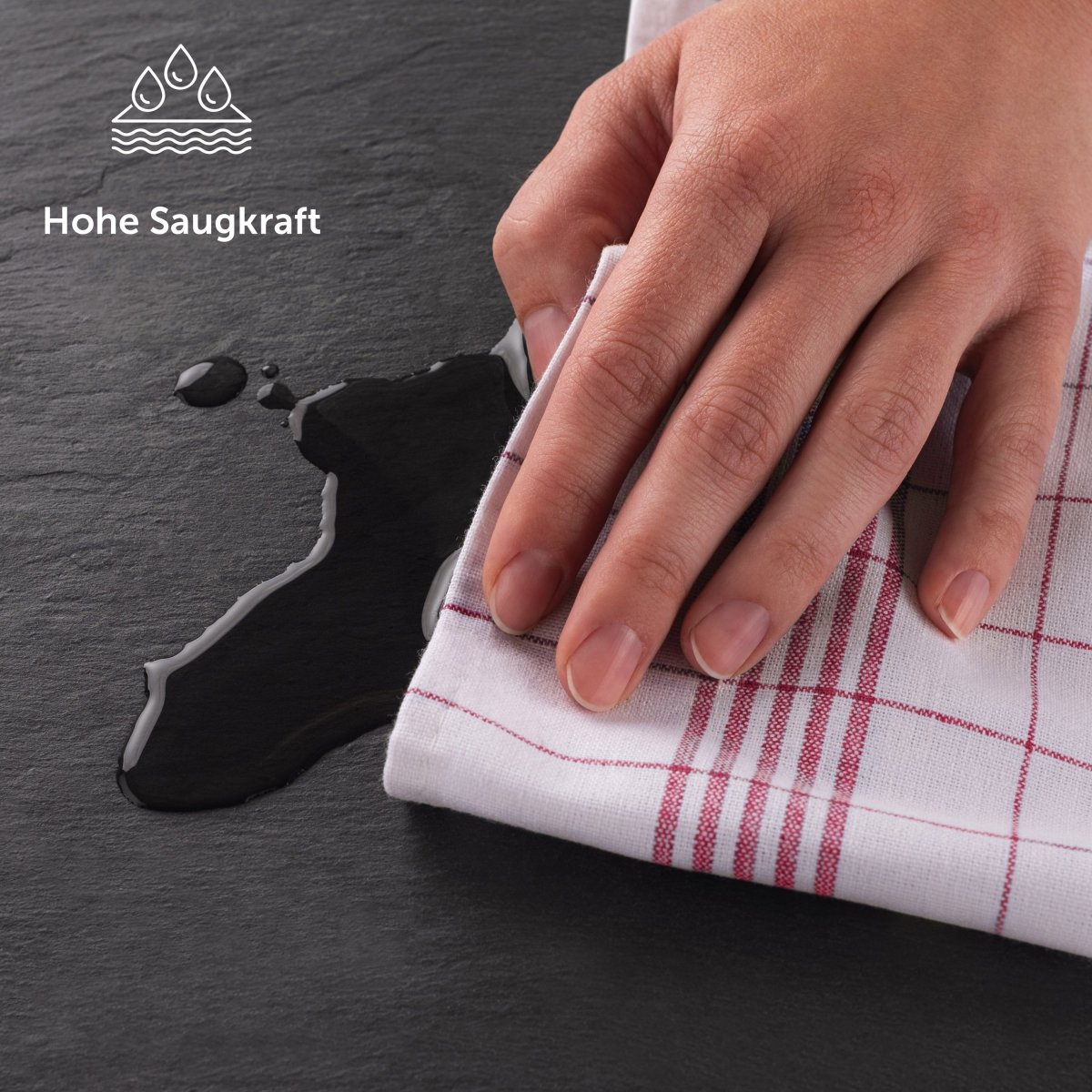 Hand wisch eine Flüssigkeit auf einer Schieferplatte mit einem Geschirrtuch auf.