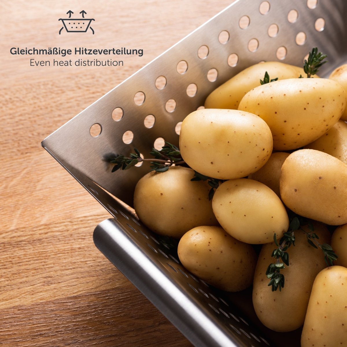 Kleiner Edelstahl-Grillkorb mit Kartoffeln und Thymian auf Holzoberfläche.