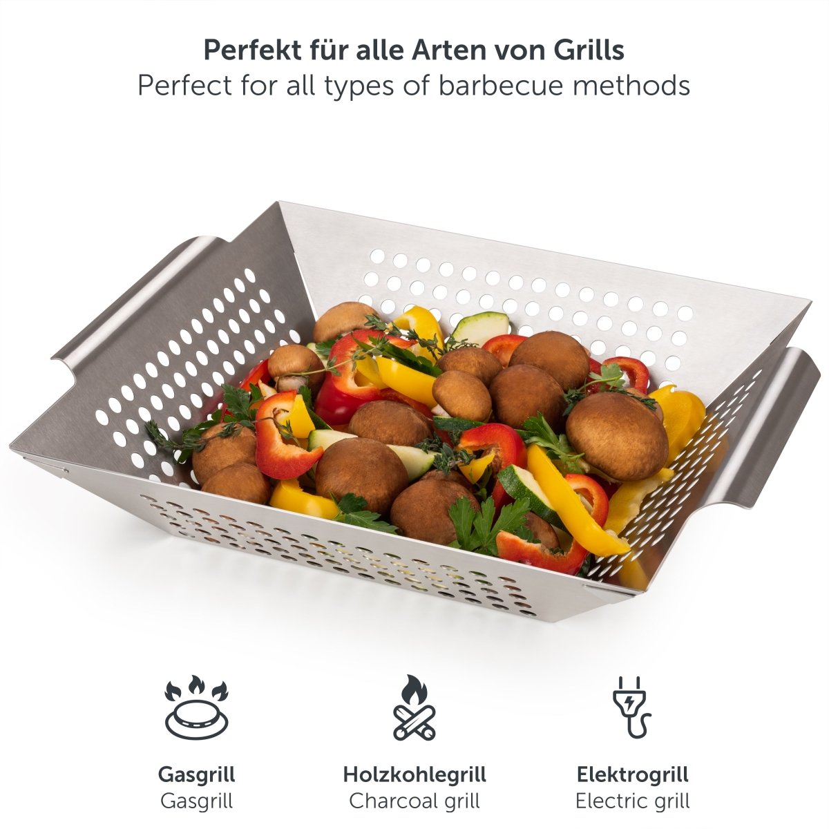 Großer Edelstahl-Grillkorb mit Gemüse und Pilzen auf einer Grillfläche.