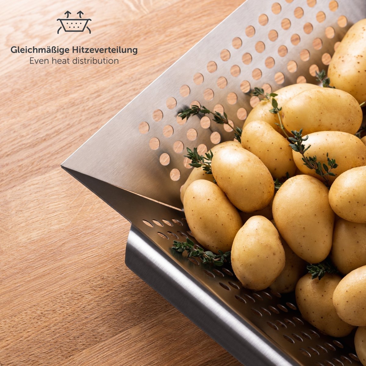 Großer Edelstahl-Grillkorb mit Kartoffeln und Thymian auf Holzoberfläche
