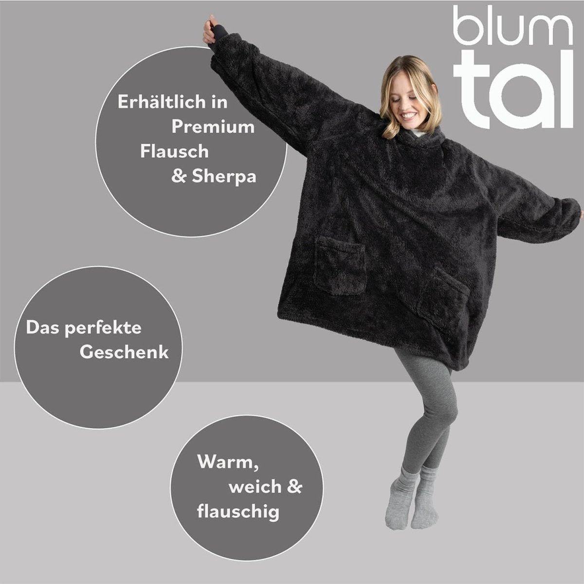 Lächelnde Frau in grauer Leggings zeigt eine anthrazitfarbene Flausch-Kuscheljacke mit den Textmerkmalen Premium Flausch & Sherpa und das perfekte Geschenk.