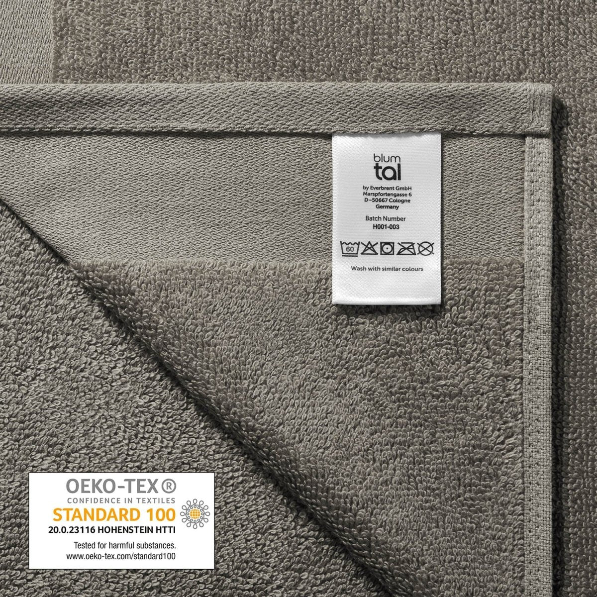 Pflegeetikett auf einem Handtuch mit Herstellerinformationen Waschsymbolen und OEKO-TEX STANDARD 100 Siegel