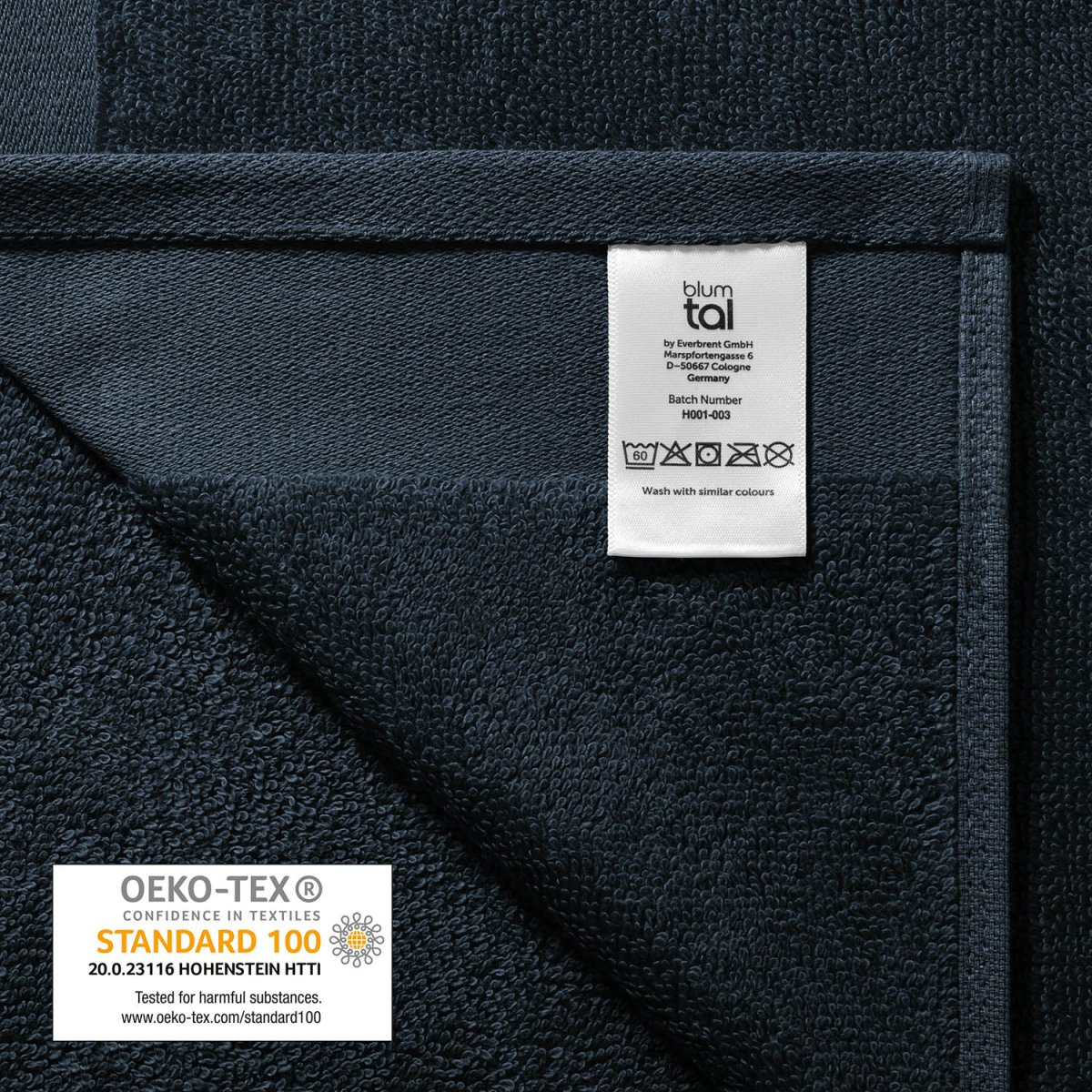 Pflegeetikett auf einem Handtuch mit Herstellerinformationen Waschsymbolen und OEKO-TEX STANDARD 100 Siegel