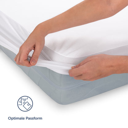 Detailansicht des weißen Matratzenschoners wie eine Hand die elastische Ecke über die Matratze zieht mit Icon für 'Optimale Passform'.