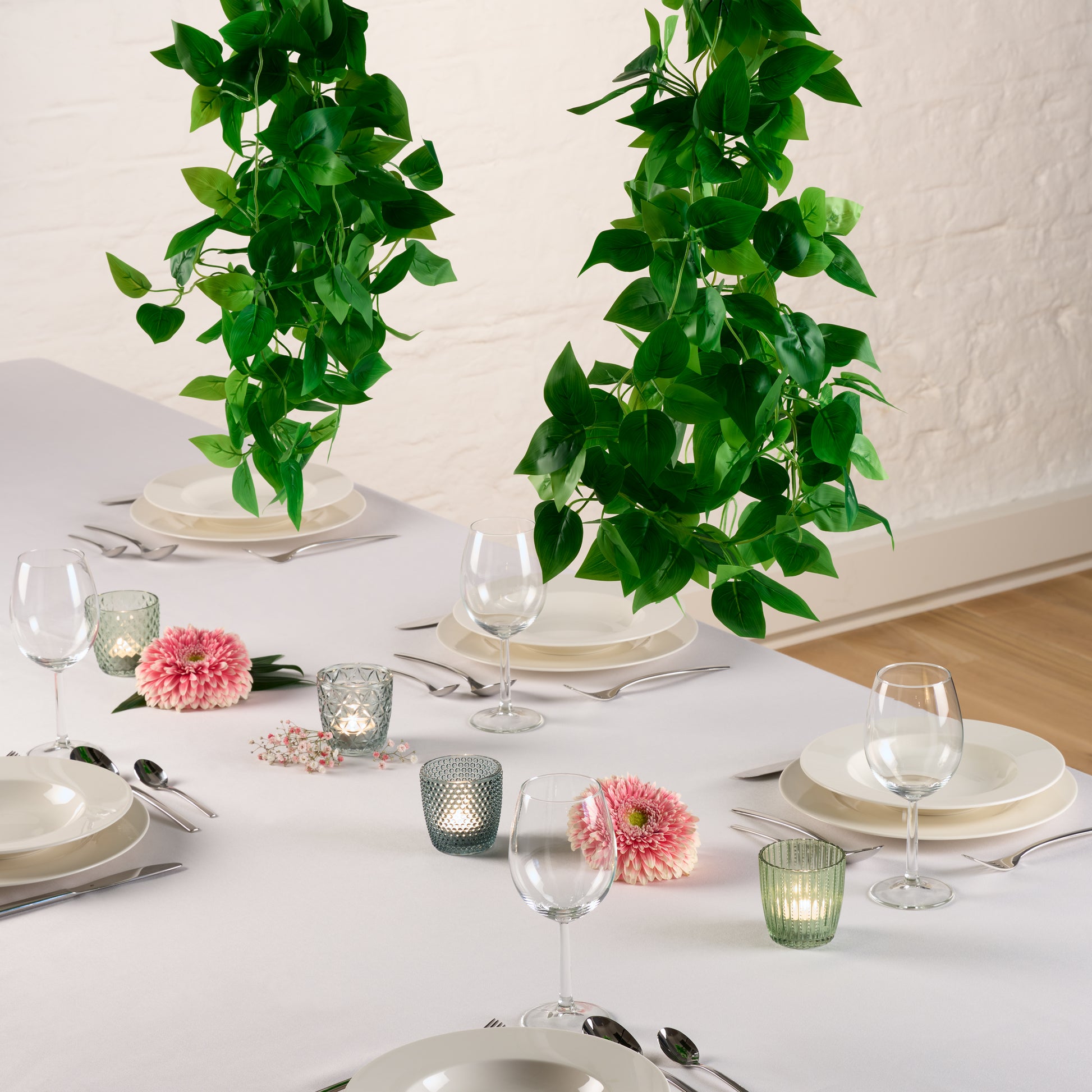 Hängende Efeu-Pflanze über einem gedeckten weißem Tisch.