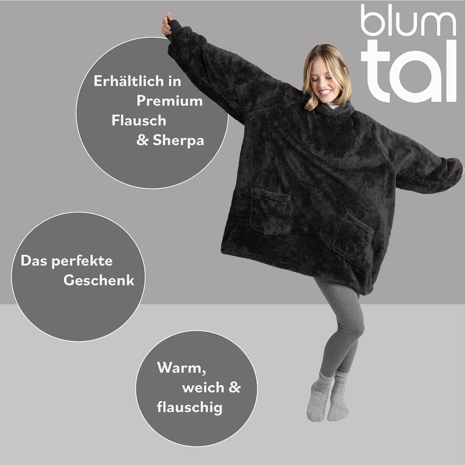 Lächelnde Frau in grauer Leggings zeigt eine anthrazitfarbene Flausch-Kuscheljacke mit den Textmerkmalen Premium Flausch &amp; Sherpa und das perfekte Geschenk.