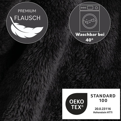 Detailaufnahme des anthrazitfarbenen Flauschmaterials der Kuscheljacke mit Symbolen für Waschbarkeit bei 40 Grad und OEKO-TEX Standard 100 Zertifizierung.
