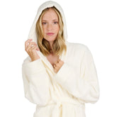 Eine Frau mit einem Fleece-Bademantel die lächelnd die Kapuze über den Kopf gezogen hat isoliert auf weißem Hintergrund.