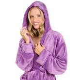 Eine Frau mit einem Fleece-Bademantel die lächelnd die Kapuze über den Kopf gezogen hat isoliert auf weißem Hintergrund.