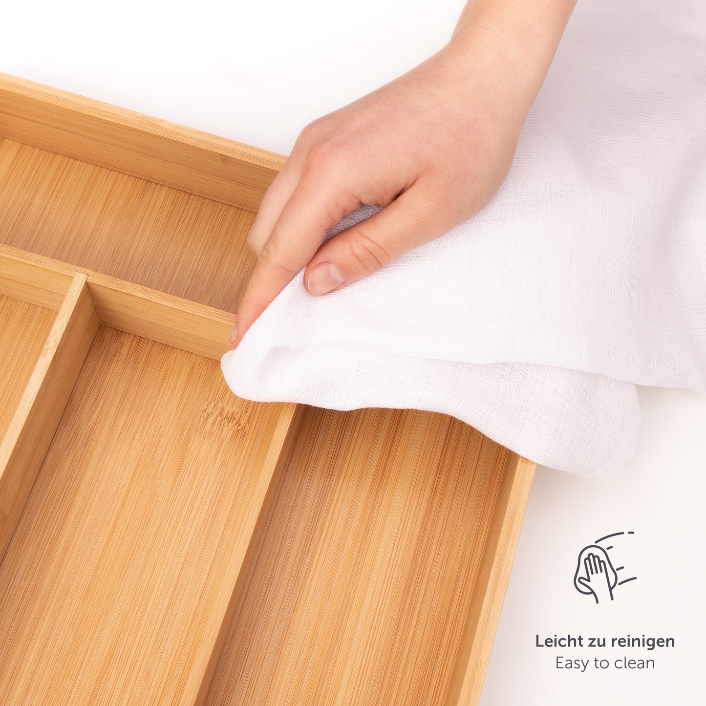 Hand wischt einen Bambusbesteckkasten mit einem Tuch ab, Symbol für einfache Reinigung sichtbar.