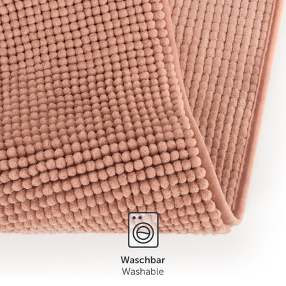 Nahaufnahme der Textur und Waschbarkeit der rosa Chenille-Badematte.