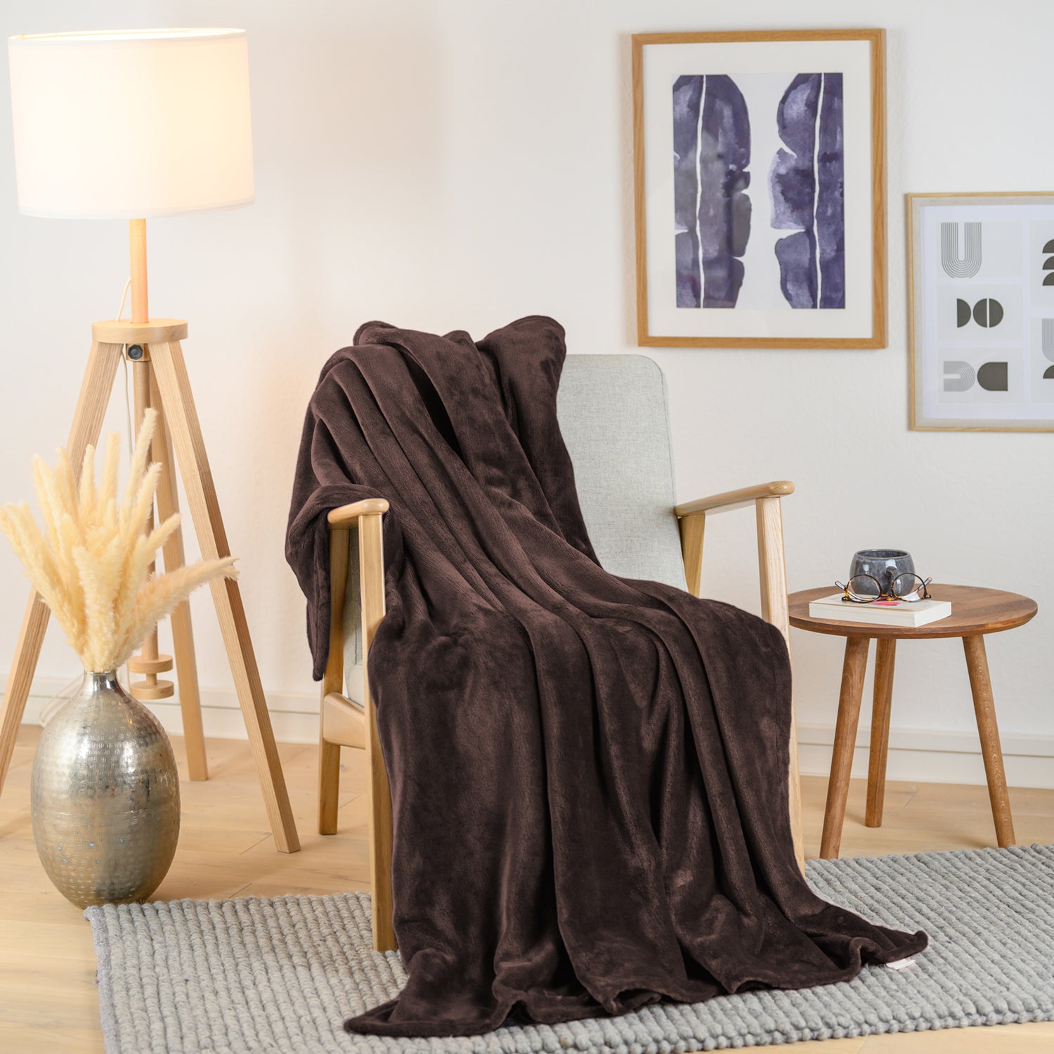 Braune Kuscheldecke elegant über einen modernen Sessel in einem Wohnzimmer drapiert, mit einem Beistelltisch und Dekoration im Hintergrund.