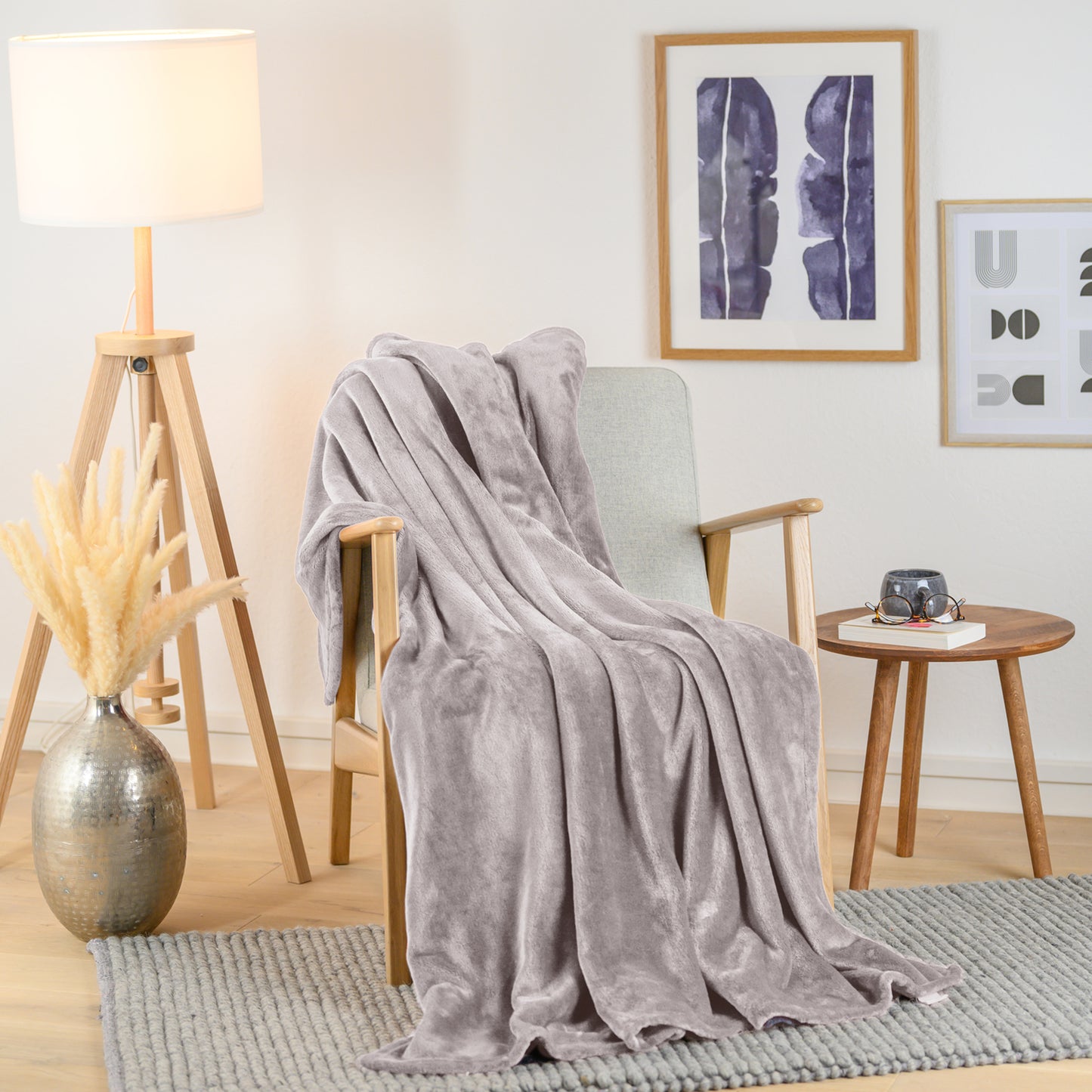 Graue Fleecedecke stilvoll über einen Sessel in einem modernen Wohnzimmer drapiert.