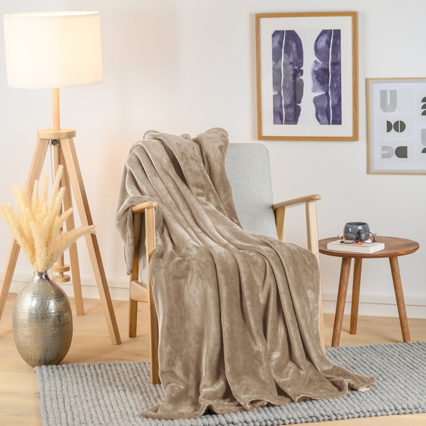 Olivgrüne Fleece-Kuscheldecke, stilvoll über einen Sessel in einem Wohnraum drapiert, mit einer Vase und Pflanzendekoration im Hintergrund.