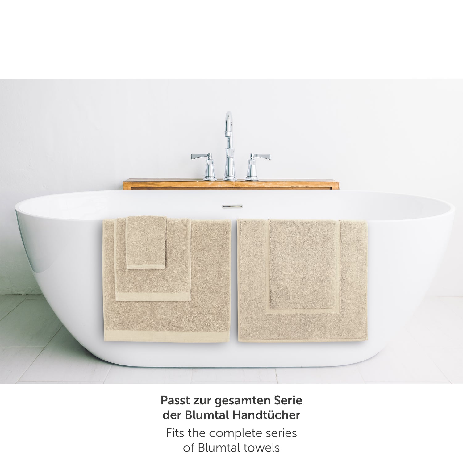 Beige Handtuch neben Badewanne passend zur Blumtal Handtuchserie.