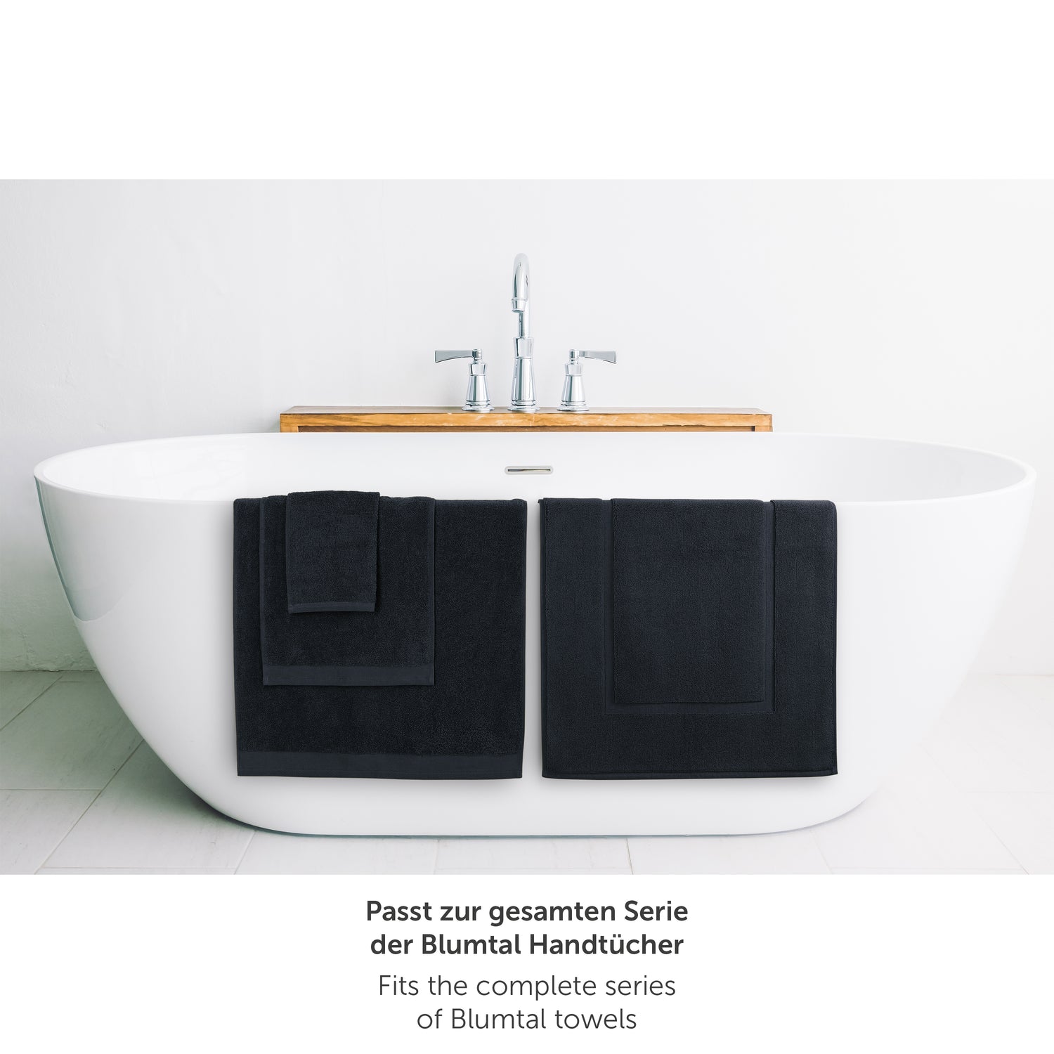 Dunkelblaues Handtuch neben Badewanne passend zur Blumtal Handtuchserie.