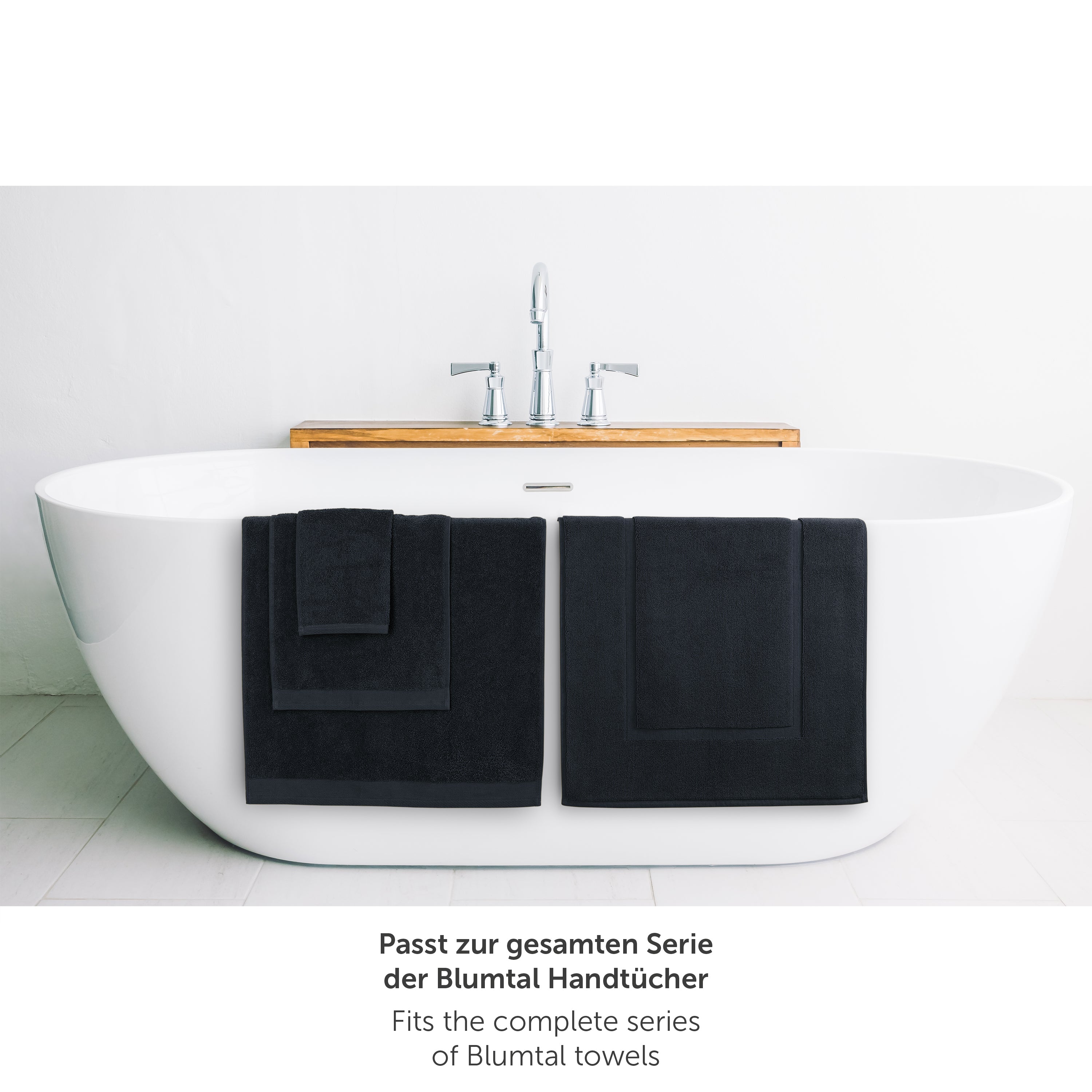 Dunkelblaues Handtuch neben Badewanne passend zur Blumtal Handtuchserie.