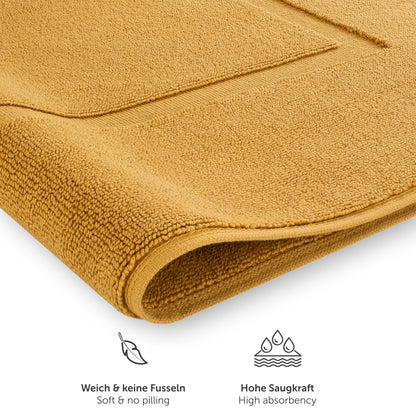Detailansicht von gelb Handtuch mit Text zu Weichheit und Saugfähigkeit.