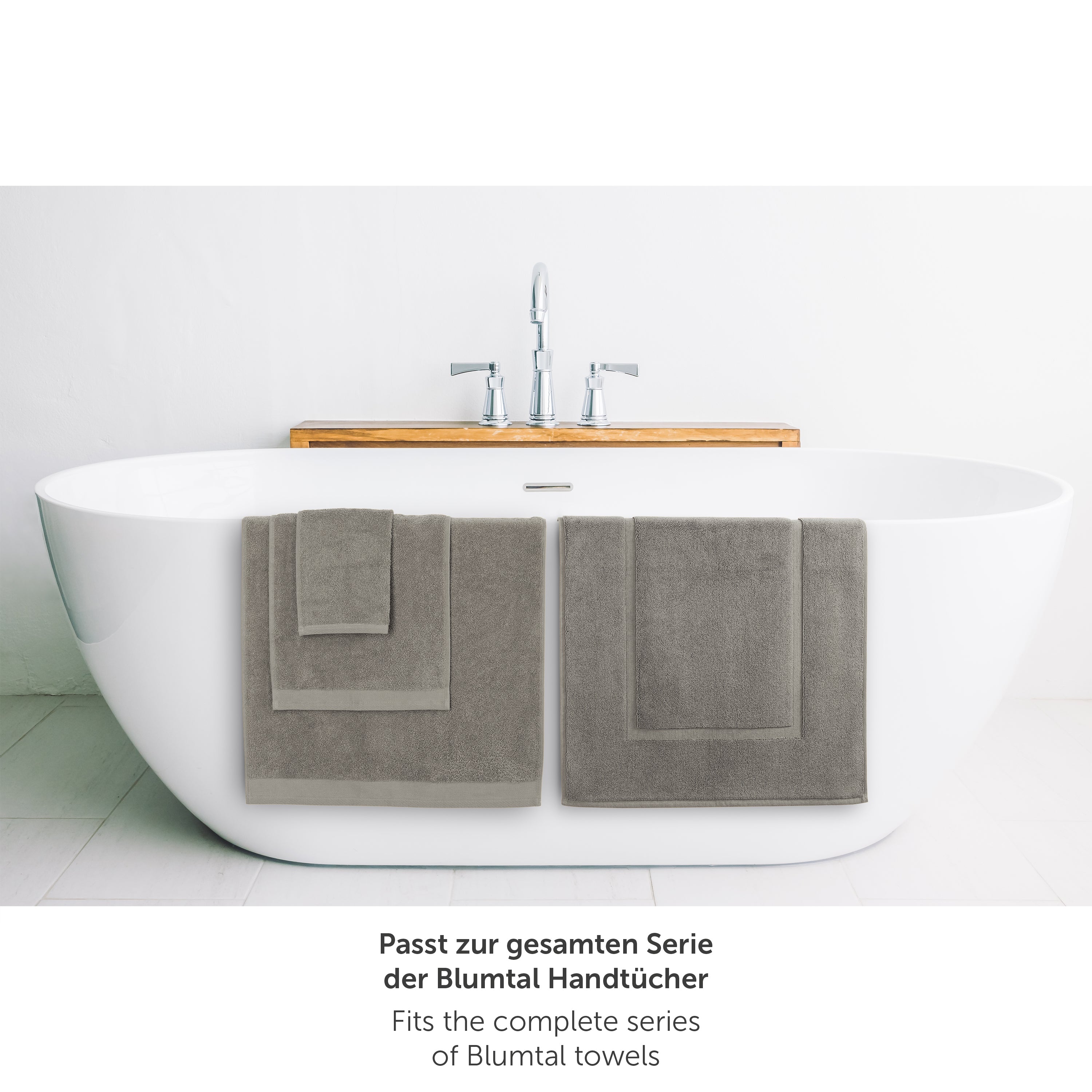 Graues Handtuch neben Badewanne passend zur Blumtal Handtuchserie.