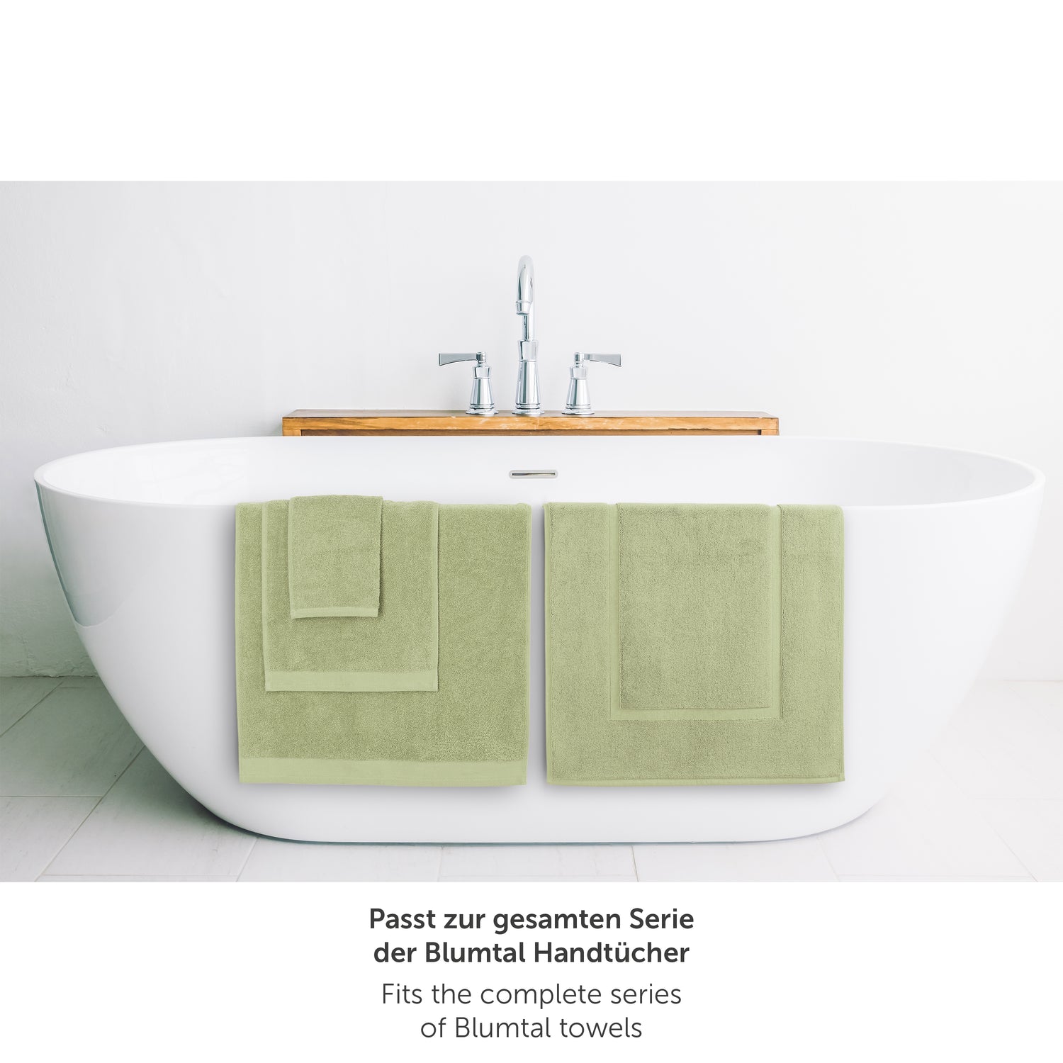 Hellgruenes Handtuch neben Badewanne passend zur Blumtal Handtuchserie.