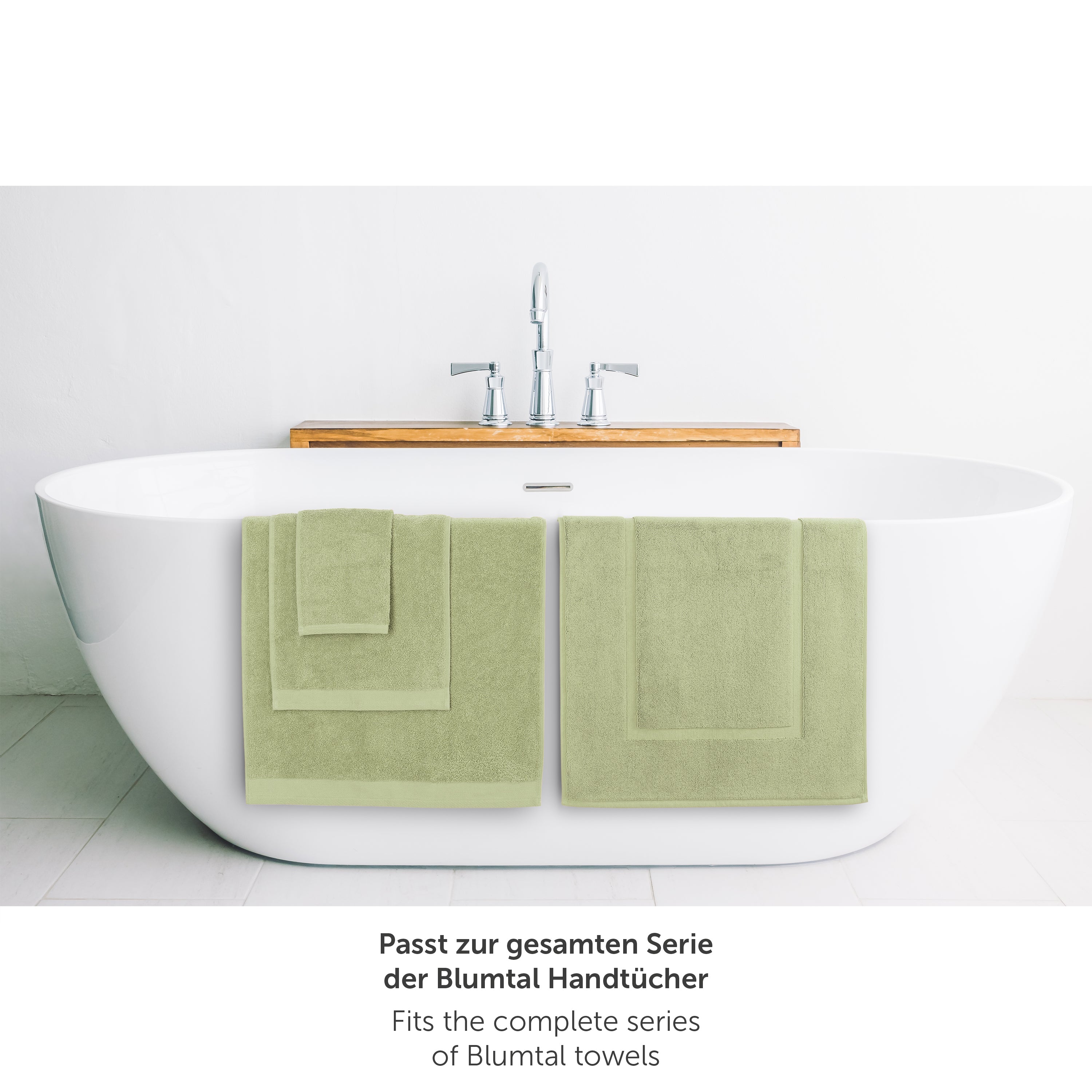 Hellgruenes Handtuch neben Badewanne passend zur Blumtal Handtuchserie.