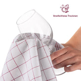 Hand trocknet ein Weinglas mit einem Geschirrtuch.