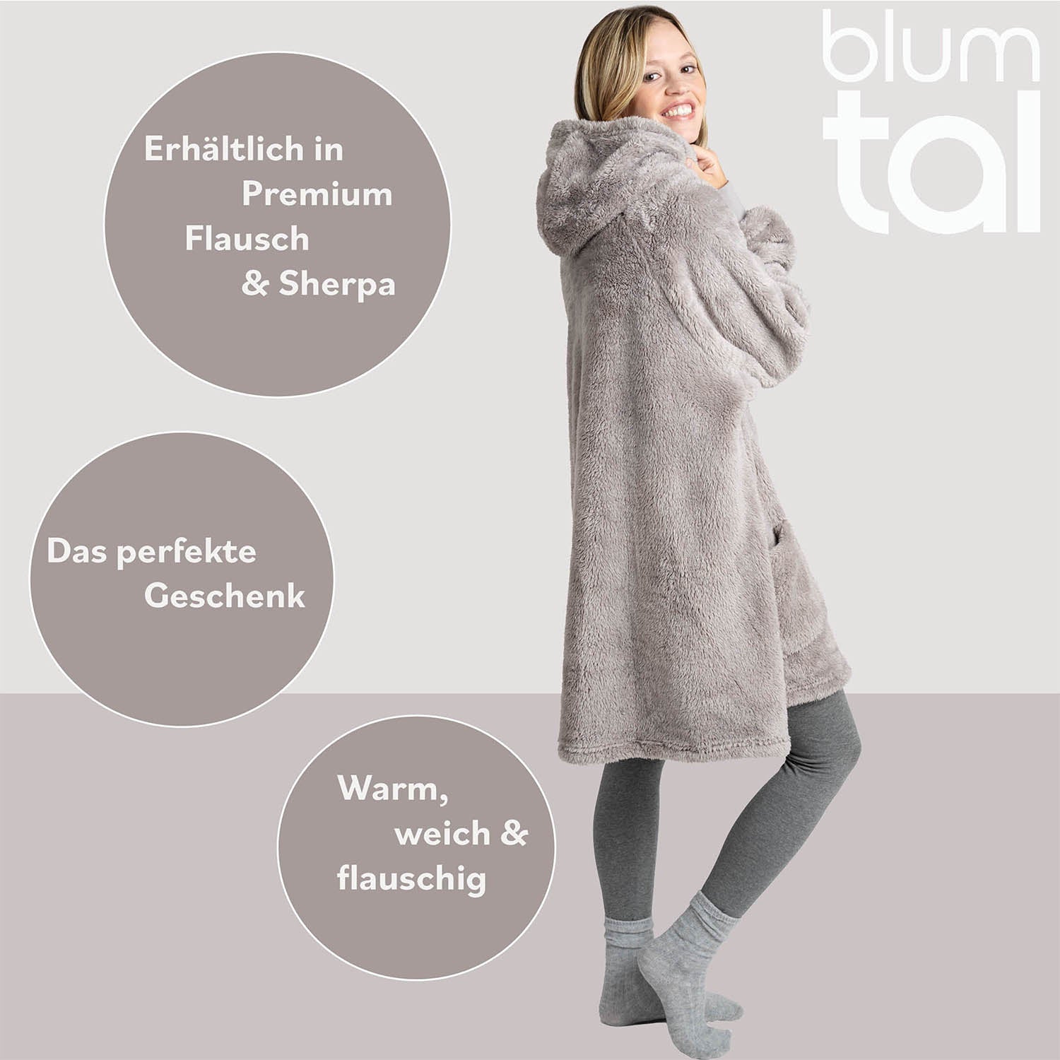 Lächelnde Frau in grauer Leggings umarmt eine graue Flausch-Kuscheljacke, Textelemente weisen auf Verfügbarkeit in Premium Flausch und als ideales Geschenk hin.