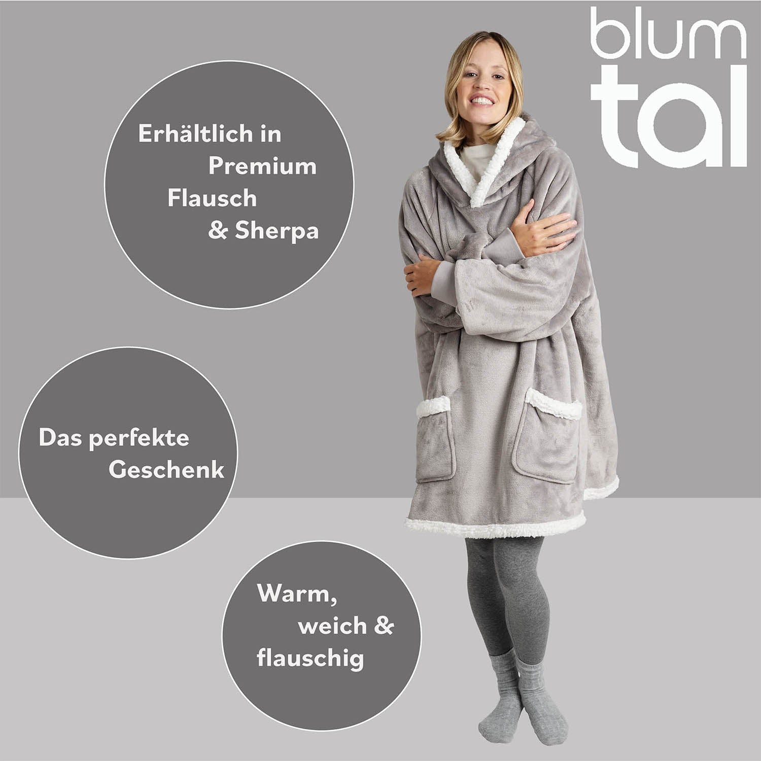 Lächelnde Frau in grauer Leggings umarmt eine graue Sherpa-Kuscheljacke, Textelemente weisen auf Verfügbarkeit in Premium Flausch &amp; Sherpa und als ideales Geschenk hin.