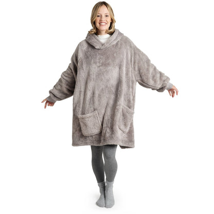 Frau in grauer Leggings und Socken lächelt, während sie eine graue Flausch-Kuscheljacke mit Kapuze und großen Taschen trägt.