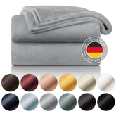 Gestapelte graue Fleecedecken mit Farbmusterpalette und dem Siegel &
