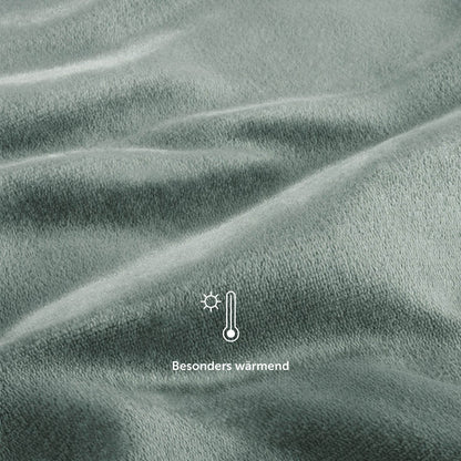 Nahaufnahme der salbeigrünen Fleece-Kuscheldecke mit einem Symbol für &