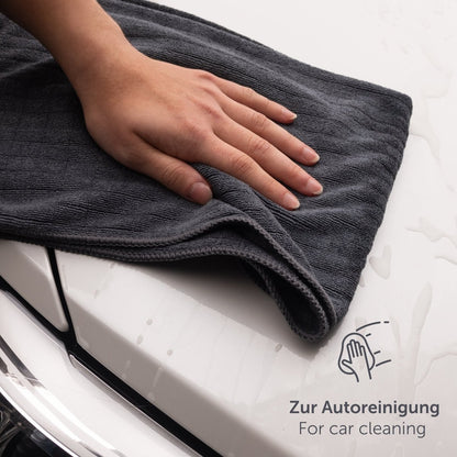 Hand legt ein Mikrofasertuch auf die Motorhaube eines Autos.