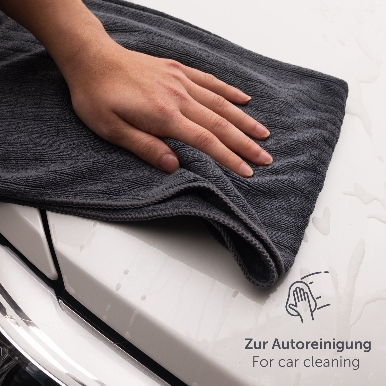 Hand legt ein Mikrofasertuch auf die Motorhaube eines Autos.