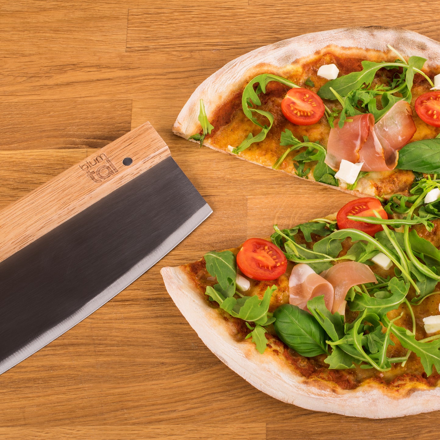 Das Wiegemesser liegt neben einer Pizza auf einem Holzbrett.