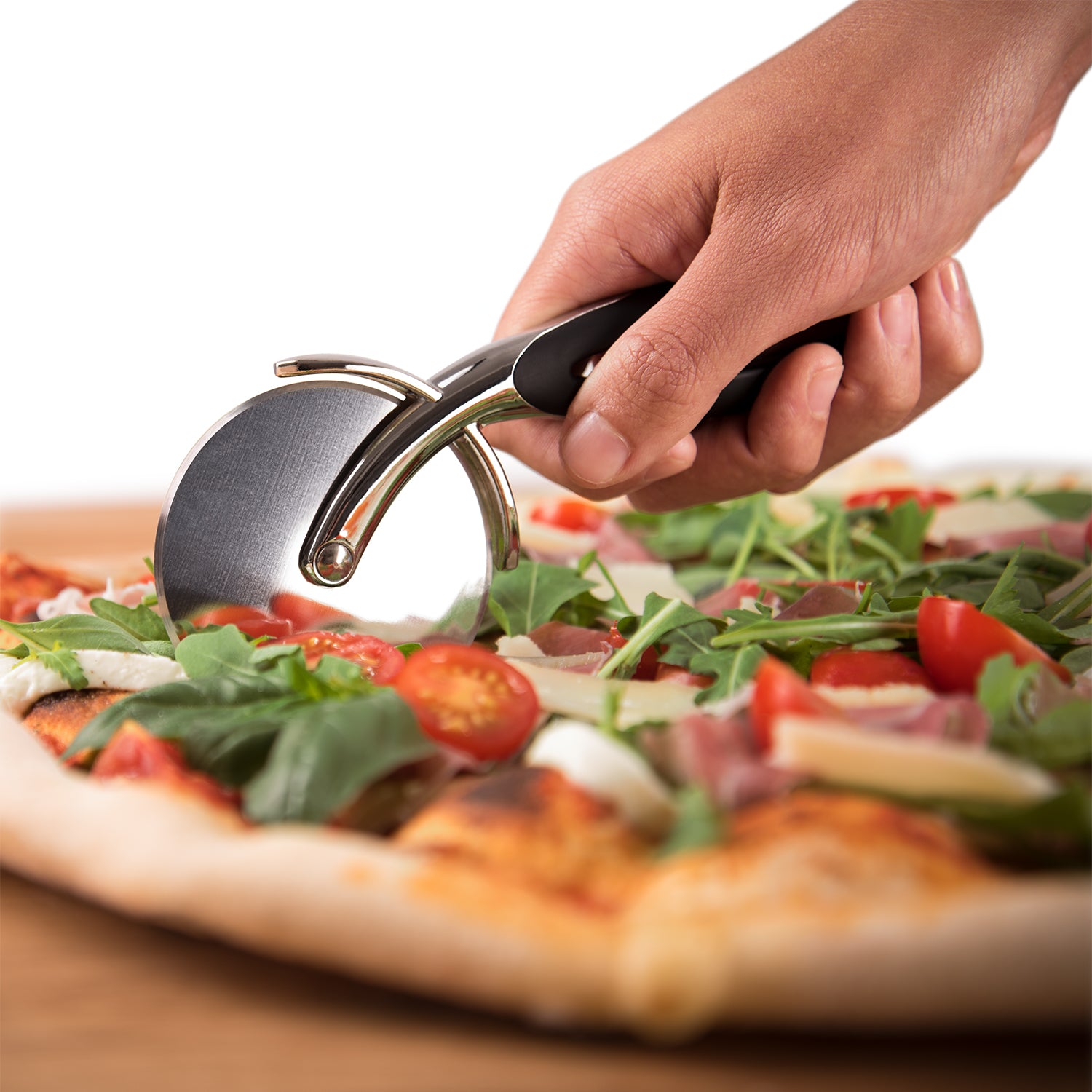 Pizzaschneider in Aktion auf einer Pizza mit Rucola und Tomaten.