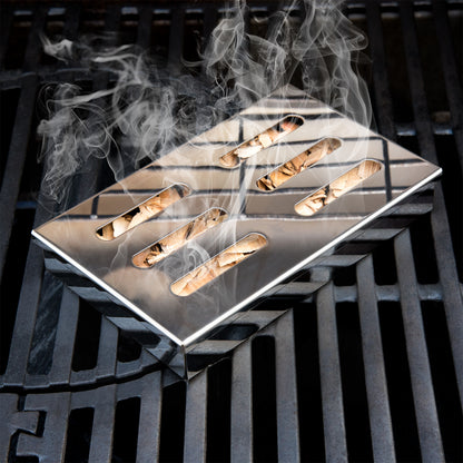 Räucherbox auf einem Grillrost mit rauchenden Buchenholzchips darin.