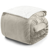 Zusammengerollte beige Decke mit weißer Fleece-Innenseite auf weißem Hintergrund.