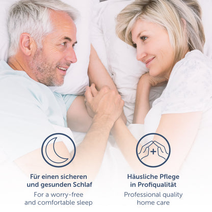 Älteres Paar lächelnd im Bett liegend mit einer Bettauflage die gesunden Schlaf und Pflegequalität zu Hause symbolisiert.