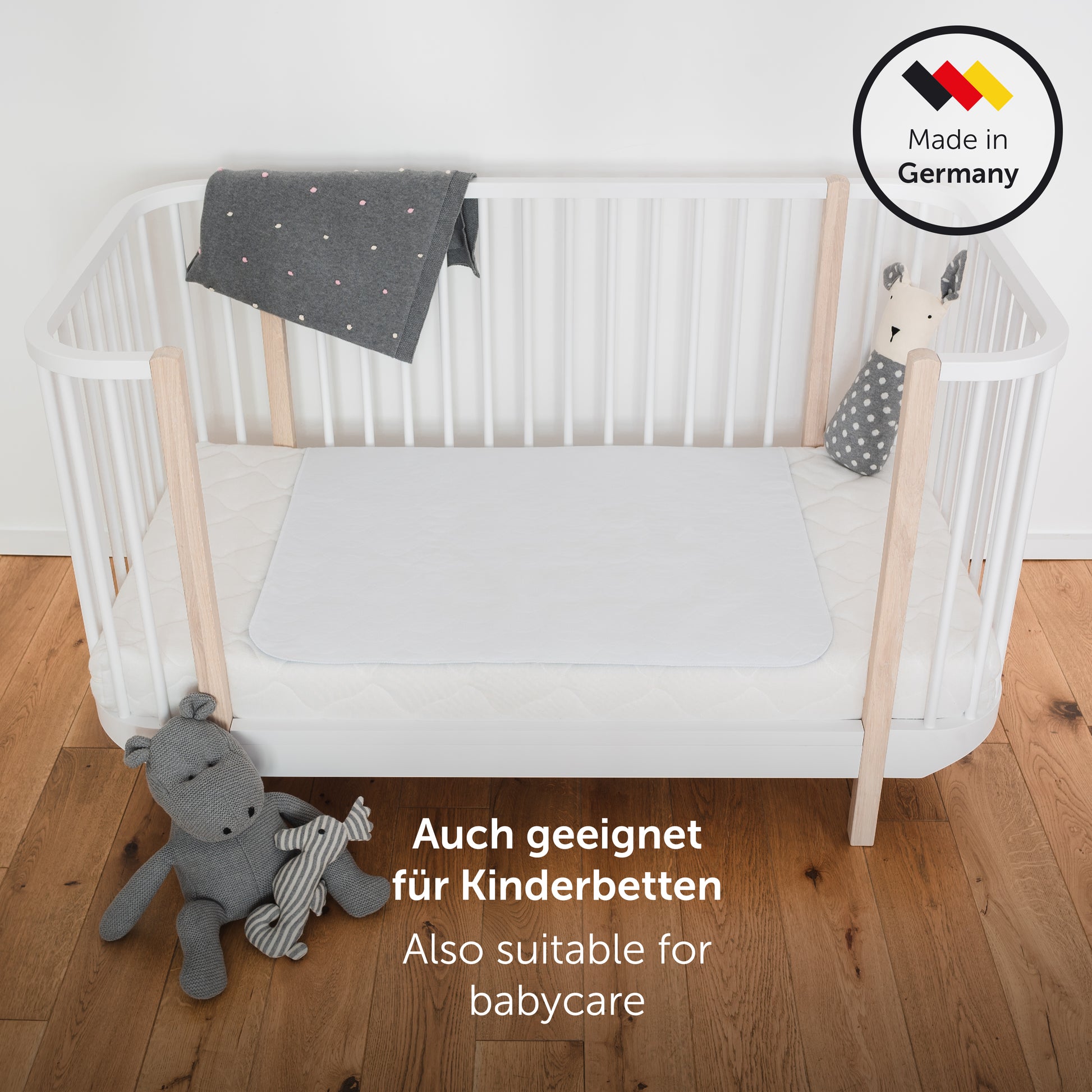 Kinderbett mit wasserfester Matratzenauflage Spielzeug und Decke hervorgehoben durch das Label 'Made in Germany' geeignet für Babypflege.
