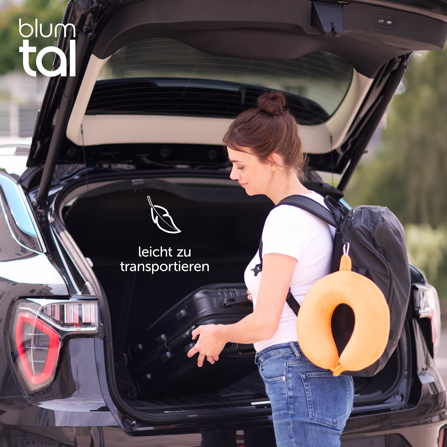 Frau mit Rucksack und orangenem Nackenkissen am offenen Kofferraum eines Autos.