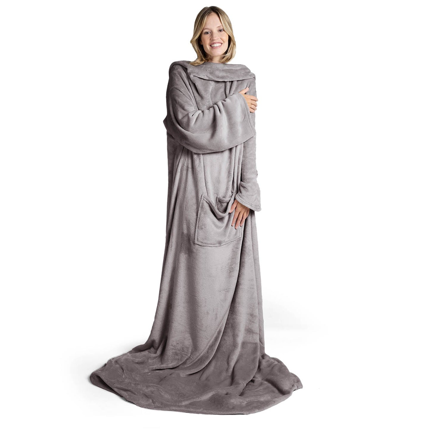 Lächelnde Frau in einem übergroßen grauen flauschigen Kleidungsstück das bis zum Boden reicht steht vor weißem Hintergrund.