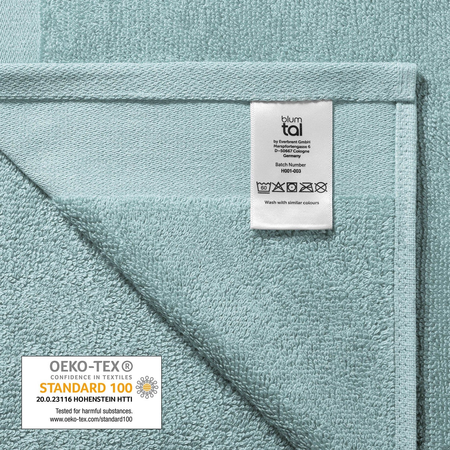 Pflegeetikett auf einem Handtuch mit Herstellerinformationen Waschsymbolen und OEKO-TEX STANDARD 100 Siegel