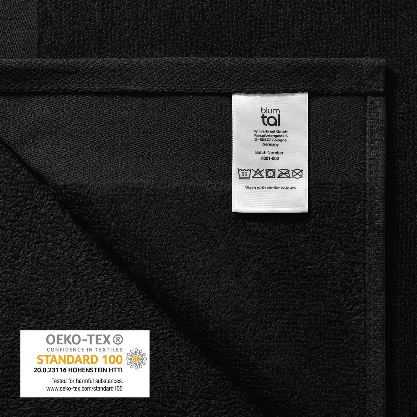 Pflegeetikett auf einem Handtuch mit Herstellerinformationen Waschsymbolen und OEKO-TEX STANDARD 100 Siegel