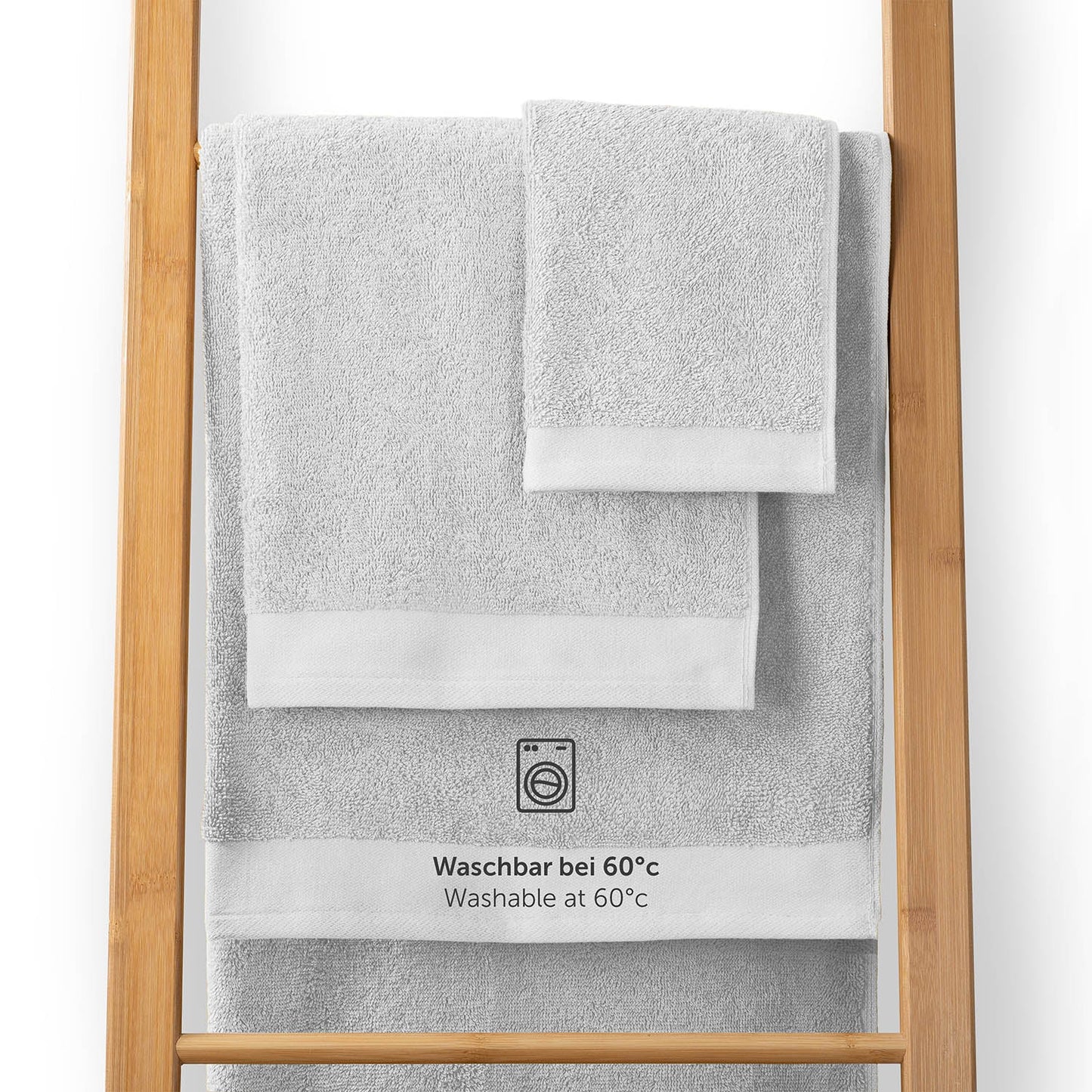 Handtücher auf einem Holzhandtuchhalter mit Pflegehinweis Waschbar bei 60°C in weißer Schrift
